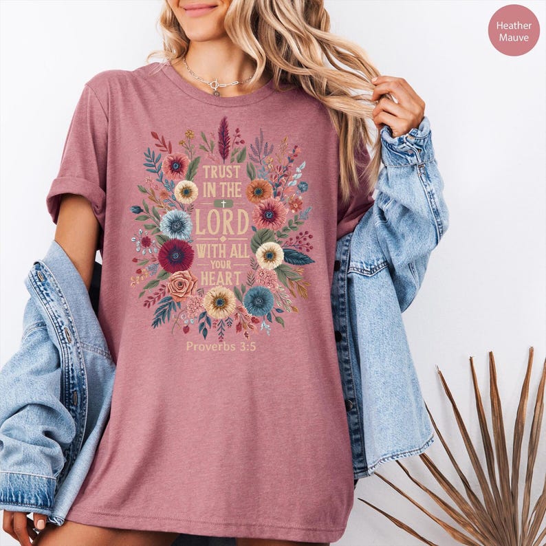 May include: Heather mauve t-shirt with a floral design and the text "TRUST IN THE LORD WITH ALL YOUR HEART" from Proverbs 3:5. The design features colorful flowers and leaves in a circular arrangement.
