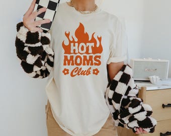 May include: A white t-shirt with an orange graphic of flames and the text "Hot Moms Club".