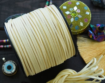 May include: A spool of cream-coloured leather cord, wound around a black plastic spool. The cord is about 3 mm wide and is shown unwound in a separate pile.