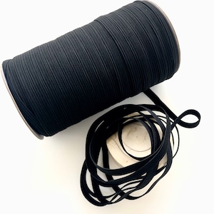 May include: A spool of black elastic cord, wound tightly and ready to be used for sewing or crafting projects.