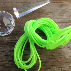 May include: A bright green neon cord is coiled on a wooden surface. A clear crystal prism and a crystal ball are also visible.