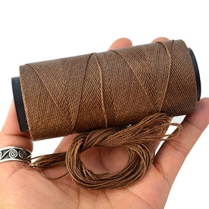 May include: A spool of brown waxed thread, unwound and ready for use. The thread is smooth and strong, perfect for leather crafting or other projects.