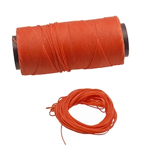 Op de afbeelding: Een spoel met feloranje draad, strak gewikkeld en klaar voor gebruik. De draad is afgerold en in een cirkel gelegd, waardoor de lengte en textuur zichtbaar worden.