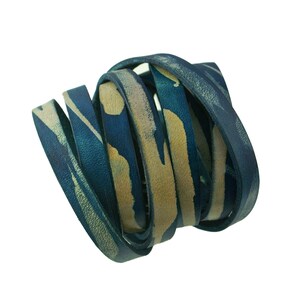 May include: A close-up of a blue and yellow leather cord, twisted into a spiral shape. The cord is made of a soft, supple leather and has a subtle, textured finish.