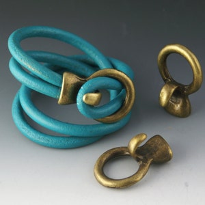 May include: A turquoise leather bracelet with a brass clasp and two brass toggle clasps.