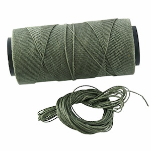May include: A spool of green waxed cotton thread with a small amount of thread unwound.