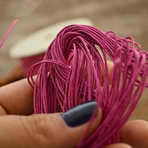 May include: A close-up of a bundle of pink paper cord. The cord is soft and pliable, and it is perfect for crafting projects.