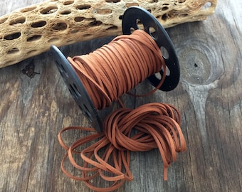 May include: A spool of brown leather cord wound around a black plastic spool. The cord is loose and spilling out of the spool.