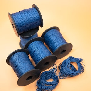 May include: Five spools of blue waxed cord, with two loose ends of cord on the right side of the image.
