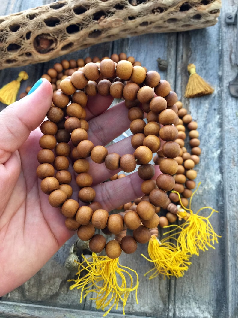 May include: A wooden beaded necklace with yellow tassels. The beads are brown and the tassels are a bright yellow.