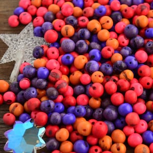 Puede incluir: Un montón grande de cuentas de madera de colores en tonos naranja, rosa, morado y azul. Las cuentas son redondas y tienen un acabado liso y pulido.