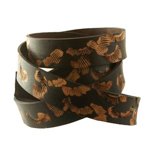 May include: A brown leather strap with a repeating pattern of tan leaf-like shapes.