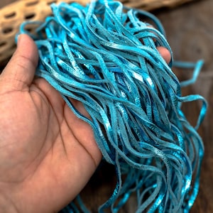 May include: A bundle of turquoise blue leather cord with a metallic sheen. The cord is soft and pliable, making it ideal for crafting jewelry, accessories, and other projects.