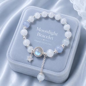 May include: A beaded bracelet featuring white and light blue translucent stones, silver-toned spacers, a central round iridescent stone, a star-shaped charm, and a dangling chain with a bead. The text reads Moonlight Bracelet Elegant Gift for Her.