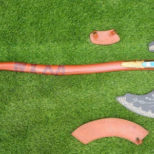 Hacha de batalla de inspiración vikinga con un diseño intrincado, grabados decorativos, mango envuelto en cuero y funda protectora a juego