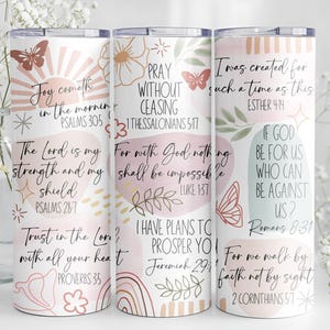 May include: Three white insulated tumblers with inspirational quotes and floral designs. The tumblers feature text from the Bible, including verses from Psalms, Proverbs, and Romans. The design includes butterflies, suns, and floral elements.