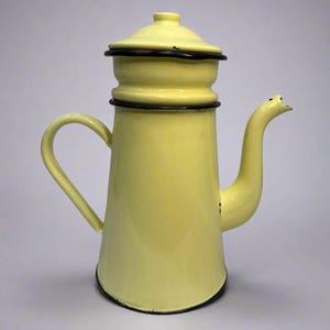 Könnte beinhalten: Eine gelbe Emaille-Kaffeekanne mit schwarzem Rand. Die Kanne hat einen Deckel, einen gebogenen Griff und einen Ausguss. Die Kaffeekanne ist hellgelb und scheint in gutem Zustand zu sein. Wahrscheinlich aus der Mitte des 20. Jahrhunderts.