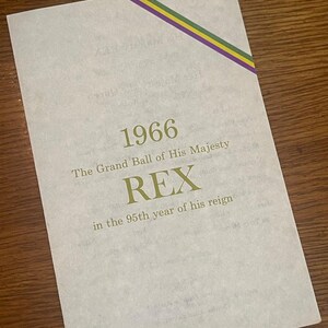 May include: A vintage, cream-colored paper invitation for the 1966 Grand Ball of His Majesty Rex, in the 95th year of his reign. The invitation features a gold and purple ribbon in the top right corner.