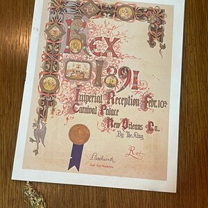 May include: A vintage, ornate, cream-colored paper document with a gold seal and blue ribbon. The document reads "Rex 1891 Imperial Reception Febr. 10th Carnival Palace New Orleans La. By The King Rex".