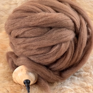 May include: A large ball of brown wool fiber, ready for spinning. The wool is soft and fluffy, and it is perfect for creating yarn for knitting or crocheting.