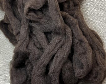 Könnte beinhalten: Ein dickes, durchgehendes Bündel aus dunkelbraunem Wollvlies. Die Fasern sind dicht gepackt und miteinander verflochten, was ein weiches, strukturiertes Aussehen mit matter Oberfläche erzeugt. Das Material ist in losen, überlappenden Schlaufen angeordnet.