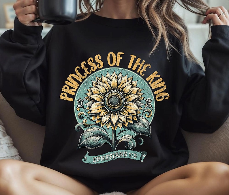 Puede incluir: Sudadera negra con un gr&aacute;fico vintage de un girasol y el texto "Princess of the King Ephesians 1:5".