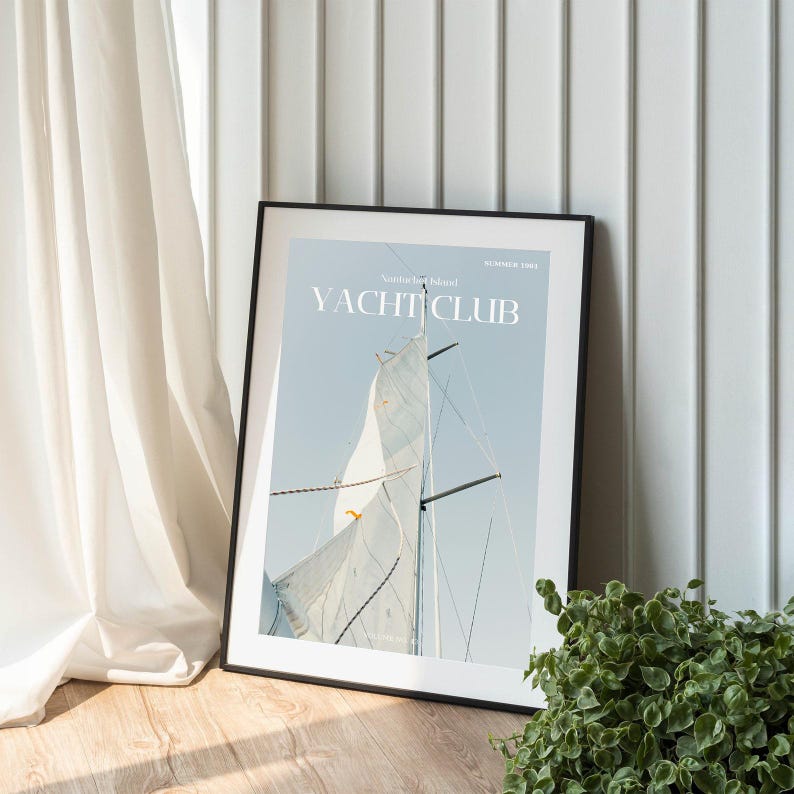 May include: A framed print of a sailboat with a white sail against a blue sky. The print has the text "YACHT CLUB" in black letters.