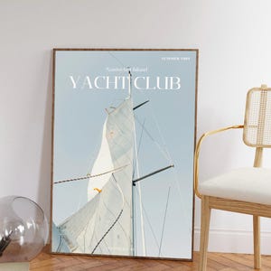 May include: A framed poster with a blue and white sailboat against a light blue sky. The poster has the text "Nantucket Island Yacht Club" and "Summer 1981" printed on it.