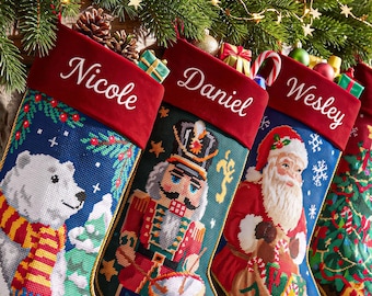 May include: Three personalized Christmas stockings with red velvet cuffs featuring the names Nicole, Daniel, and Wesley. The stockings display needlepoint designs of a polar bear, a nutcracker, and Santa Claus with gifts.