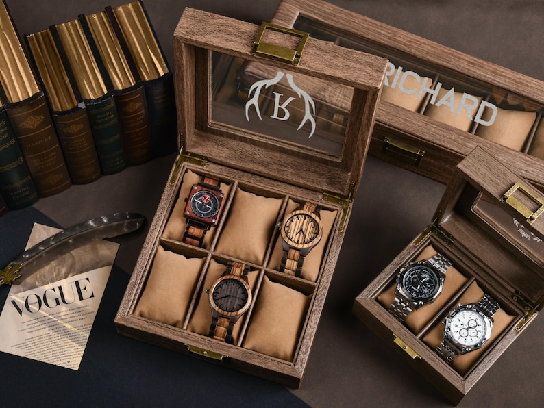 May include: Wooden watch boxes with glass lids, showcasing various wooden and metal watches. One box has a deer antler and letter "K" design, another has the name "RICHARD". The watches have brown, black, and silver tones. The boxes are open, revealing the watches.
