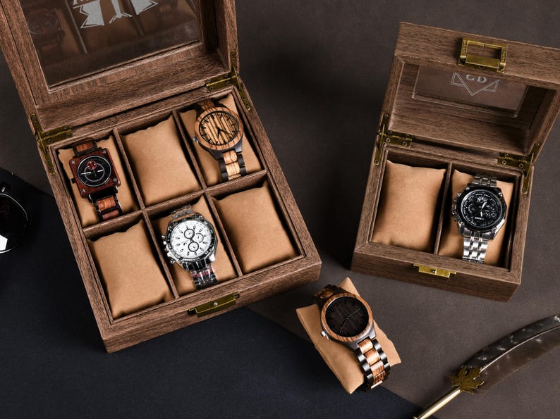 May include: Wooden watch display cases with glass tops, showcasing various wristwatches. The watches feature wooden and metal bands, with different face designs. The cases are open, revealing the watches on tan cushions.