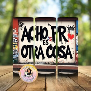 Op de afbeelding: Een cilindrische beker met een graffiti-stijl ontwerp. De tekst "ACHO FR ES OTRA COSA" wordt weergegeven in grote, druipende zwarte letters. Het ontwerp bevat een rood hart, een kroon en een Puerto Ricaanse vlag. De beker staat op een houten oppervlak.