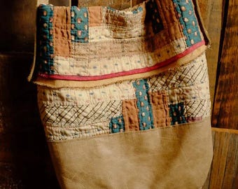 May include: A brown leather and patchwork fabric tote bag with a long brown strap. The bag is made of different coloured fabrics, including brown, beige, green, and red.