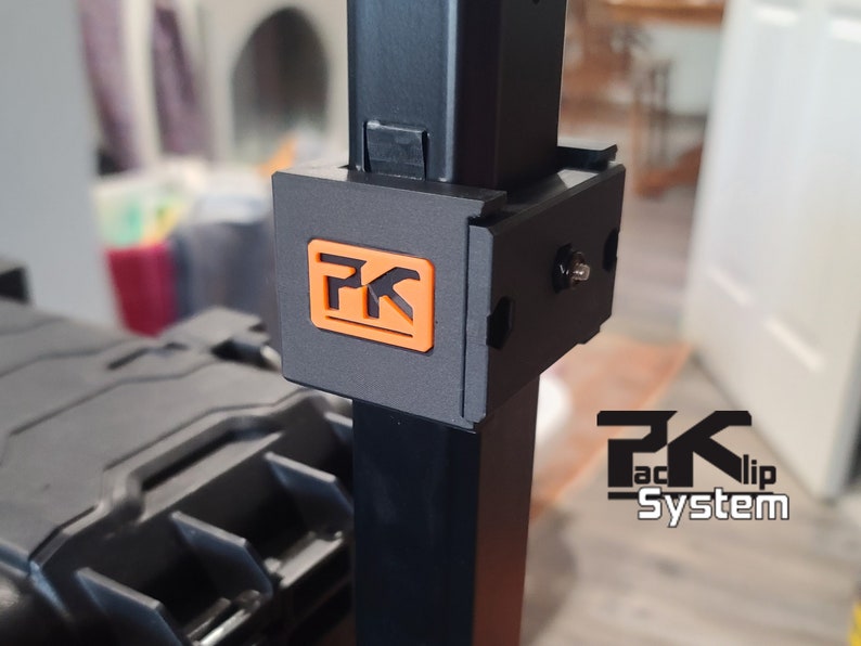 Puede incluir: Primer plano de un soporte met&aacute;lico negro con un logotipo naranja y negro. El logotipo presenta las letras "PK" dentro de un cuadrado. Las palabras "PK Faclip System" est&aacute;n impresas en blanco debajo.