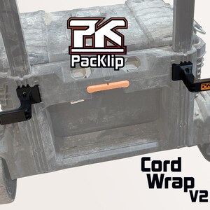 May include: A gray rolling toolbox with black cord wrap clips. The clips have the Packlip logo and the text "Cord Wrap v2". The toolbox has an orange handle and black wheels.