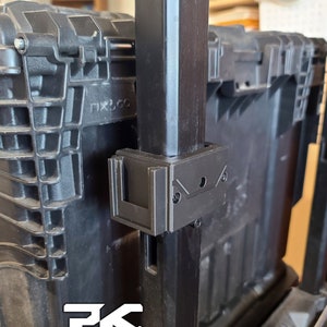 Puede incluir: Un contenedor de almacenamiento de pl&aacute;stico negro con un poste de soporte de metal negro y un soporte negro. El soporte est&aacute; fijado al poste con tornillos. El texto "PK Clip System" es visible en blanco.
