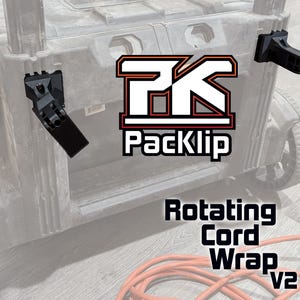 Peut inclure: Un enrouleur de cordon rotatif noir avec le texte "Rotating Cord Wrap v2" et le logo "PK Packlip" sur une bo&icirc;te &agrave; outils noire.