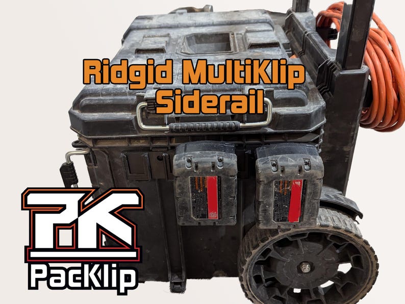 May include: A black Ridgid MultiKlip Siderail toolbox with two black battery packs attached to the side. The toolbox has a black handle and wheels. The toolbox is labelled "PackKlip" in white letters with a red outline.