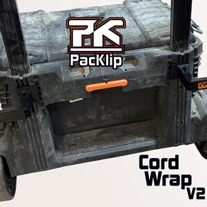May include: Black rolling tool box with the text "Cord Wrap v2". The tool box has an orange handle and black wheels. The logo "PK Packclip" is visible on the top of the tool box.