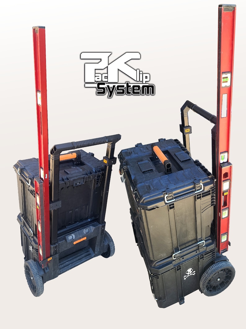 May include: Two black toolboxes with orange handles and a skull and crossbones design on the bottom box. The toolboxes are on a red and black rolling cart with a level attached to the side. The cart has a black handle and two black wheels. The text "Packlip System" is visible in the background.