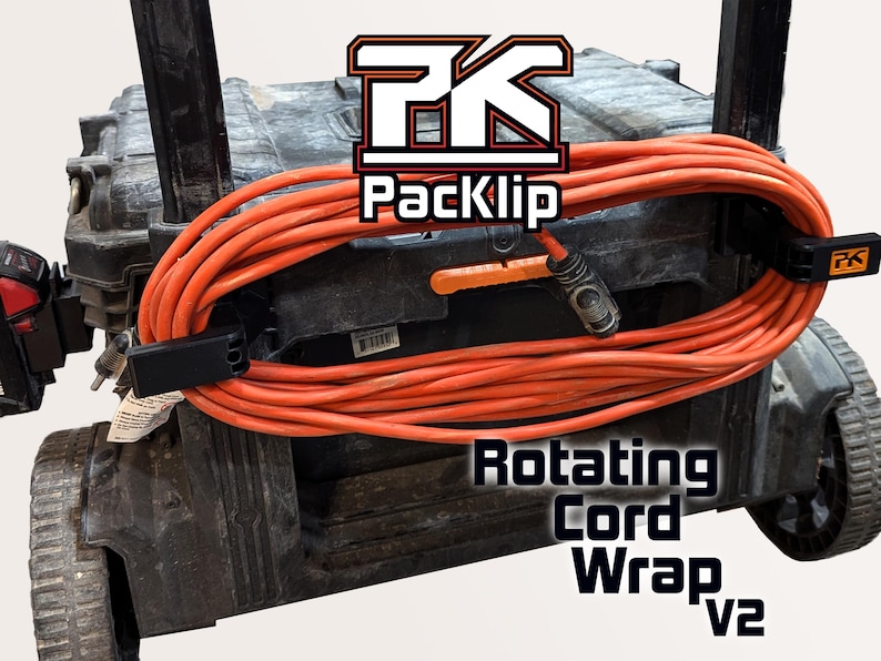Peut inclure: Un outil de rangement de cordon noir et orange fix&eacute; &agrave; une bo&icirc;te &agrave; outils noire. L'outil est &eacute;tiquet&eacute; "Rotating Cord Wrap v2" et "PackKlip".