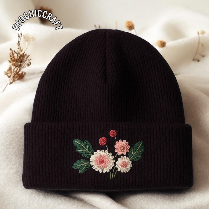 May include: A dark brown beanie with an embroidered floral design. The embroidery features pink and white flowers, green leaves, and red berries. The text "ECOCHICCRAFT" is visible on the top left of the beanie.