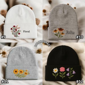 May include: Four beanies with embroidered floral designs. One is white with a red and green floral design and the word "Floral". Another is gray with orange flowers and the name "Julia". The third is gray with yellow sunflowers. The last is black with a daisy, rose, and purple bellflowers.