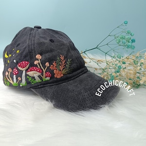 May include: A black denim baseball cap with embroidered mushrooms, leaves, and a crescent moon. The cap has a white embroidered logo that says "Ecochiccraft".