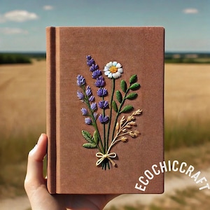 May include: A brown journal with an embroidered floral design. The embroidery features purple lavender, a white daisy, green leaves, and wheat tied with a yellow bow. The text "ECOCHIC CRAFT" is printed on the bottom right.