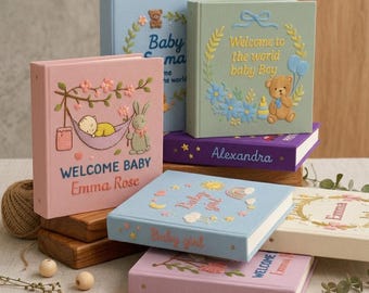 May include: A collection of baby memory books in various pastel colors. Each book features embroidered designs, including a teddy bear, a bunny, and floral accents. The books have titles like "Welcome Baby" and "Baby Girl."