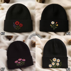 May include: Four black beanies with embroidered floral designs. One beanie features red poppies and lavender, another has daisies and yellow flowers, a third displays pink coneflowers, and the last one shows white daisies.