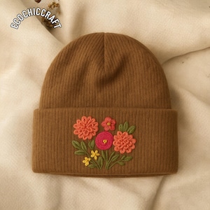 May include: A brown knit beanie with a folded brim. The beanie features an embroidered floral design in shades of orange, pink, yellow, and green. The text "ECOCHICRAFT" is visible in the upper left corner.