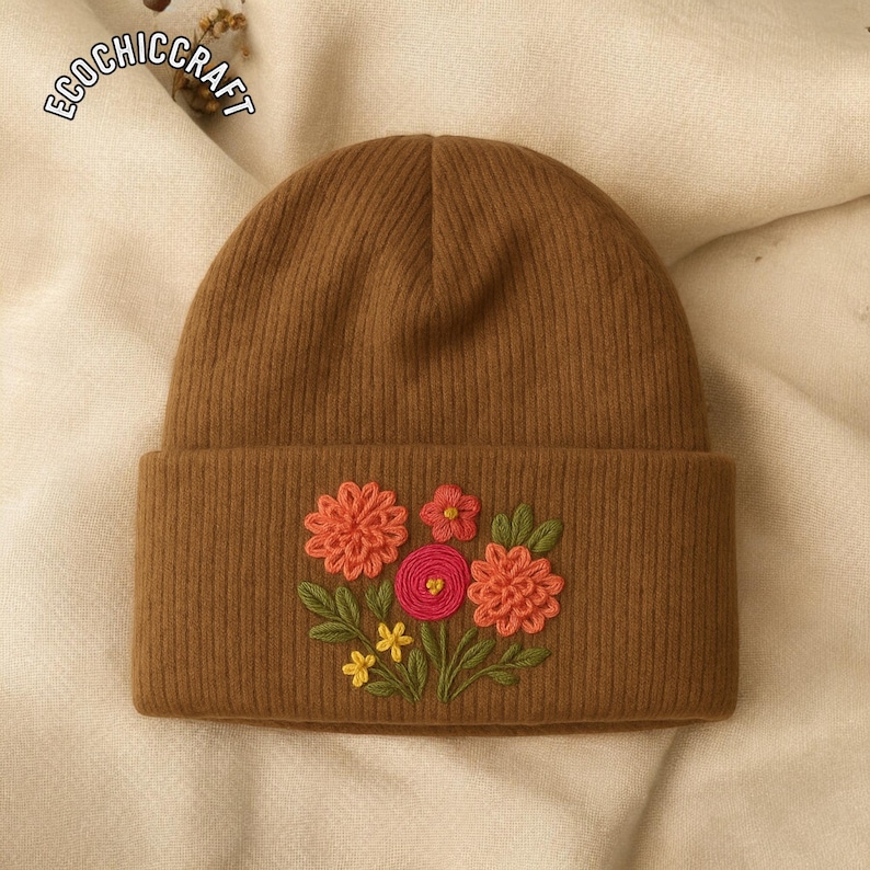 May include: A brown knit beanie with a folded brim. The beanie features an embroidered floral design in shades of orange, pink, yellow, and green. The text "ECOCHICRAFT" is visible in the upper left corner.