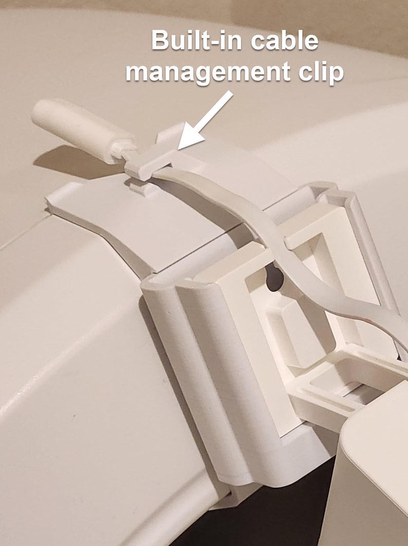 May include: Close-up of a white plastic cable management clip. The clip is designed to hold a cable in place. The text "Built-in cable management clip" is visible in the image.